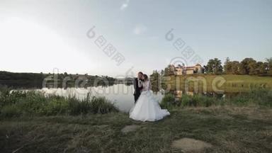 白人新郎和新娘在湖边的公园里。 新婚夫妇。 新婚夫妇接吻